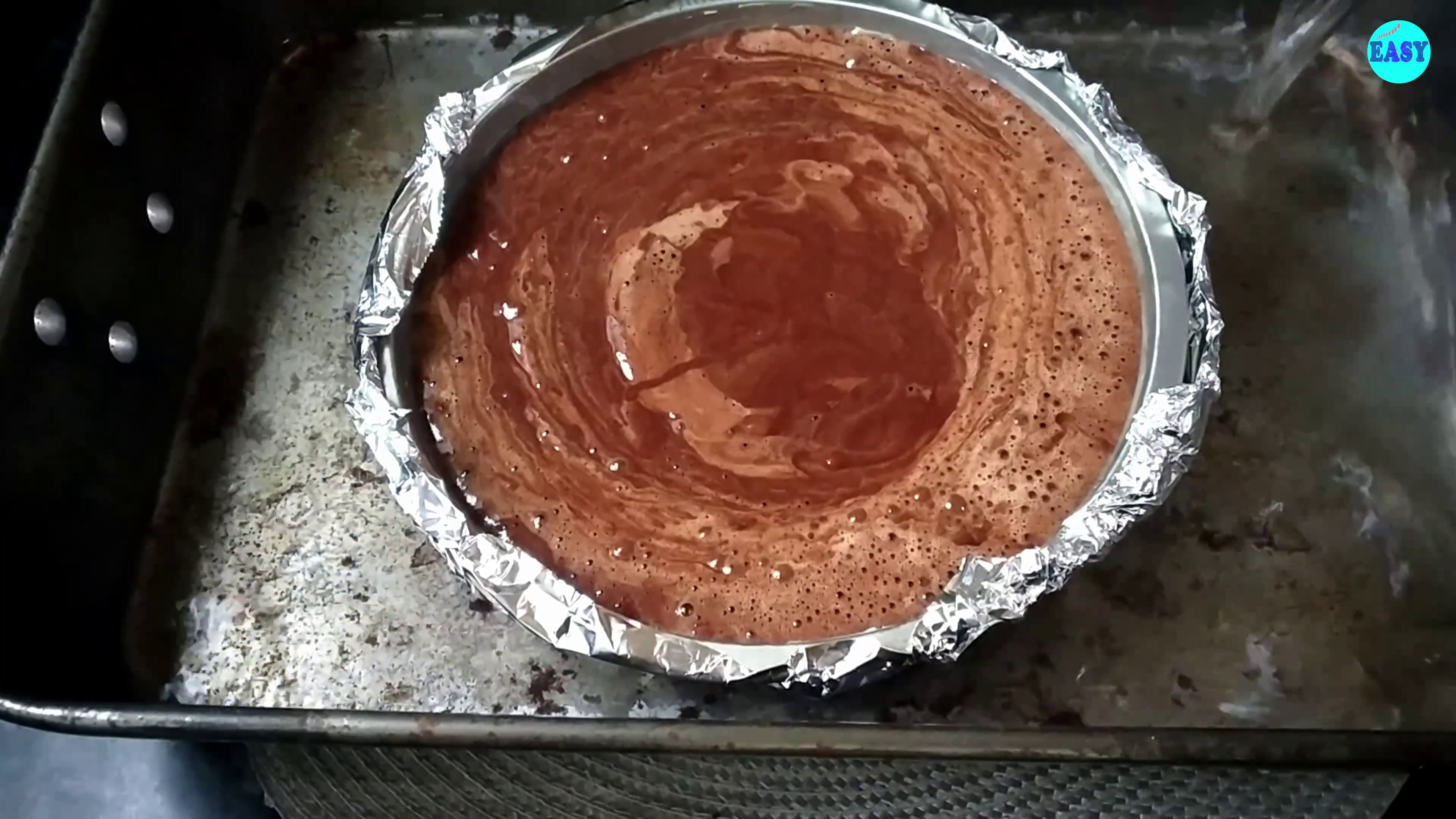 Step 10 - Transfer the cake batter to the well greased tin and wrap the bottom with aluminium foil. Now  place it in a big roasting tray. Fill the tray with the boiling water making sure it is not more than half of the height of cake tin.
